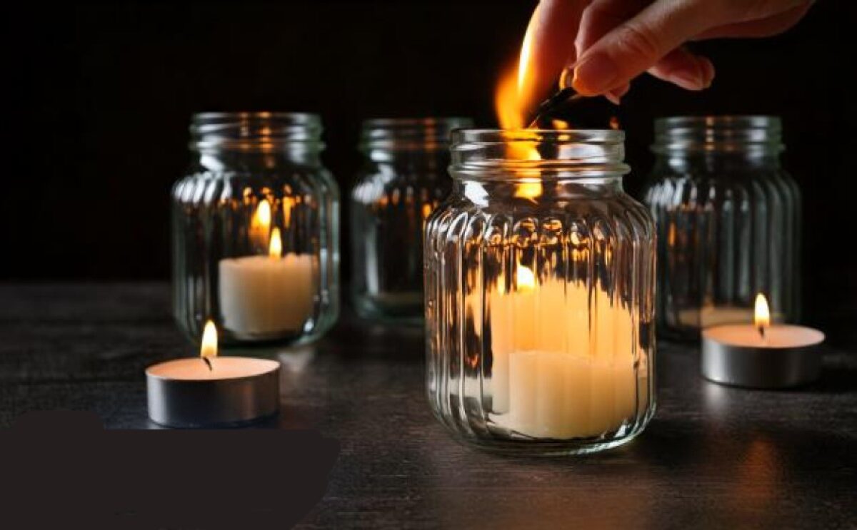 left candle burning in glass jar