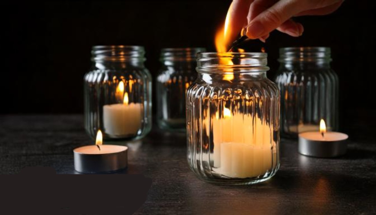 left candle burning in glass jar